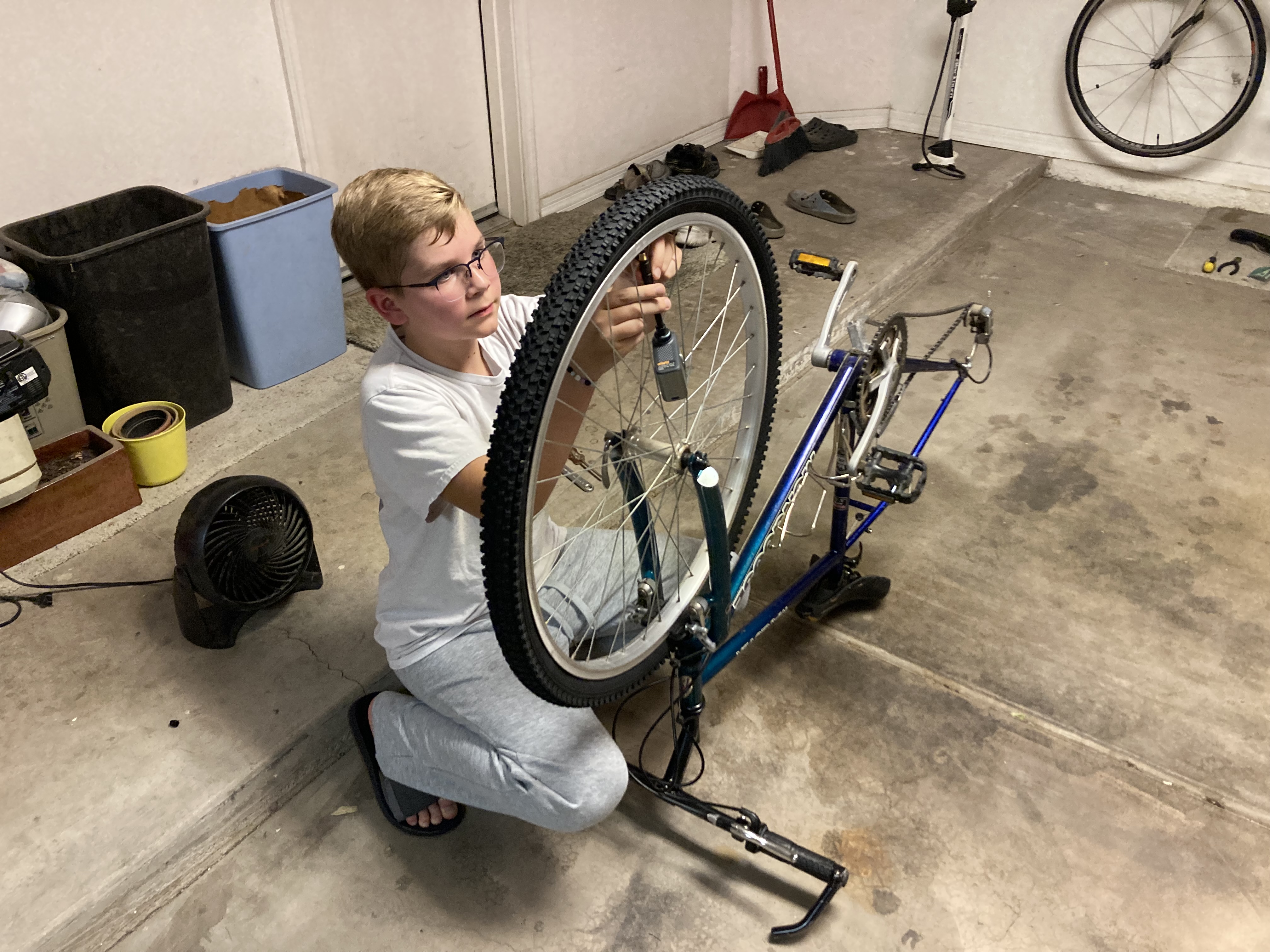 Parker kneeling in the garage, truing a bike wheel